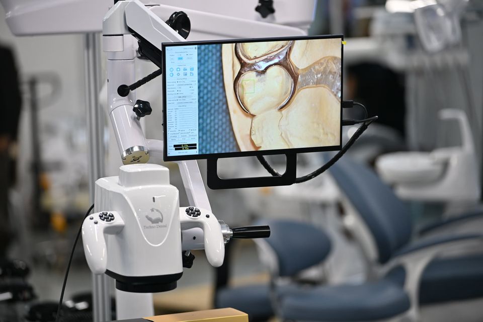 A dental microscope sending a magnified view of a tooth to a monitor