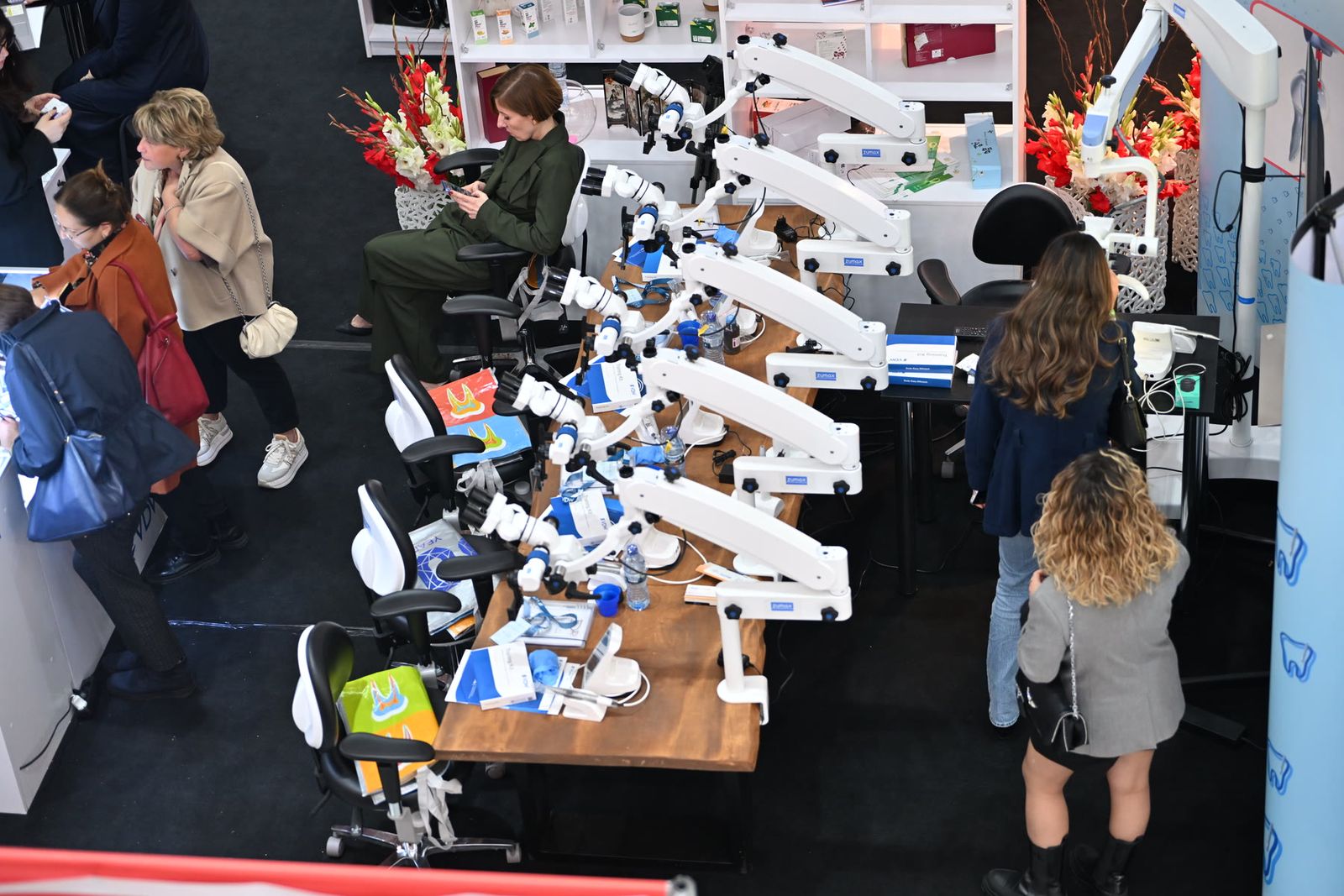 Visitors at a stand of dental microscopes, seen from above