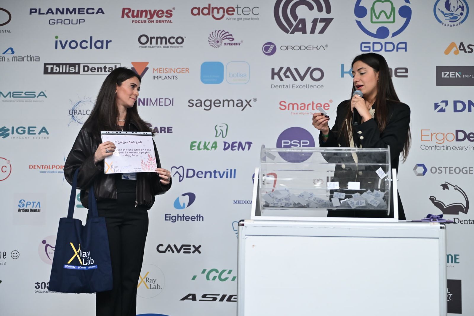 A prize draw on stage in front of the sponsors’ wall